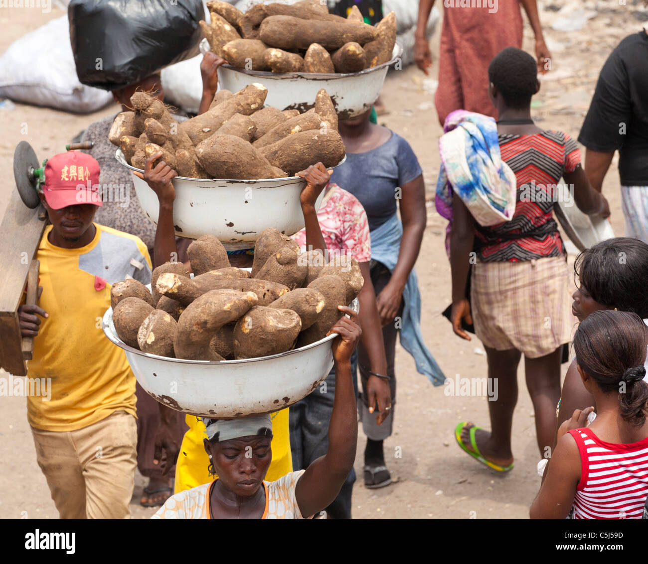 Les personnes transportant des conteneurs du manioc au marché occupé Agbogbloshie, Accra, Ghana Banque D'Images