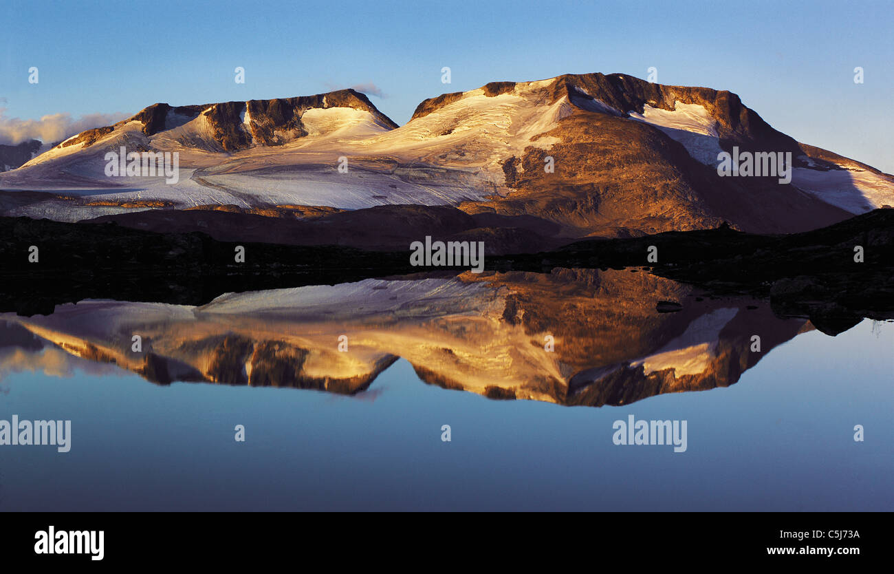 Début de matinée de la lumière sur le Fannaraken avec pics comme un miroir un reflet dans un lac glaciaire, Jotunheim, la Norvège région Banque D'Images