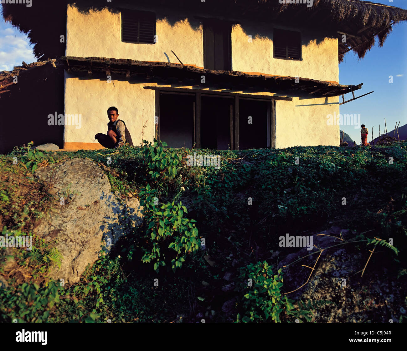 Deux petits personnages à côté d'une presque-terminées nouvelle maison dans le village de Num dans la région de la rivière Arun est du Népal Banque D'Images