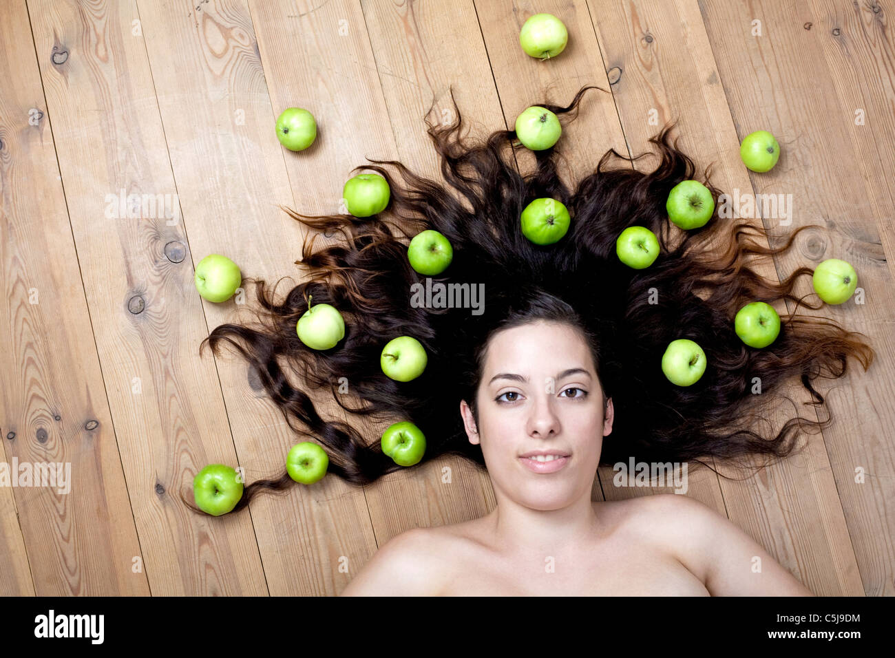 Jeune femme allongée sur le sol avec des pommes Banque D'Images
