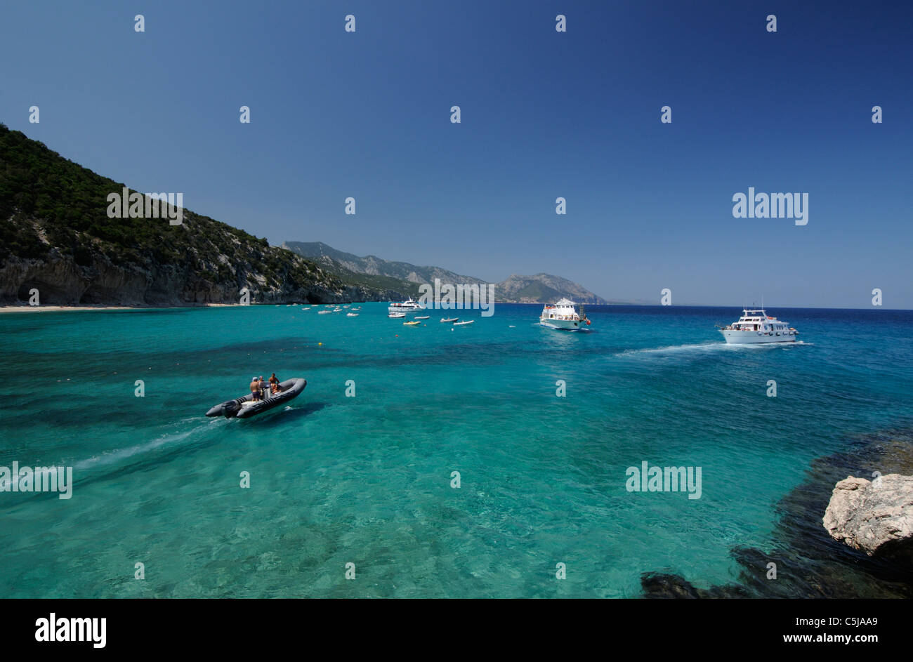 Partent et zodiac bateau naviguant sur les eaux transparentes de la plage de Cala Luna, Cala Gonone Sardaigne Banque D'Images