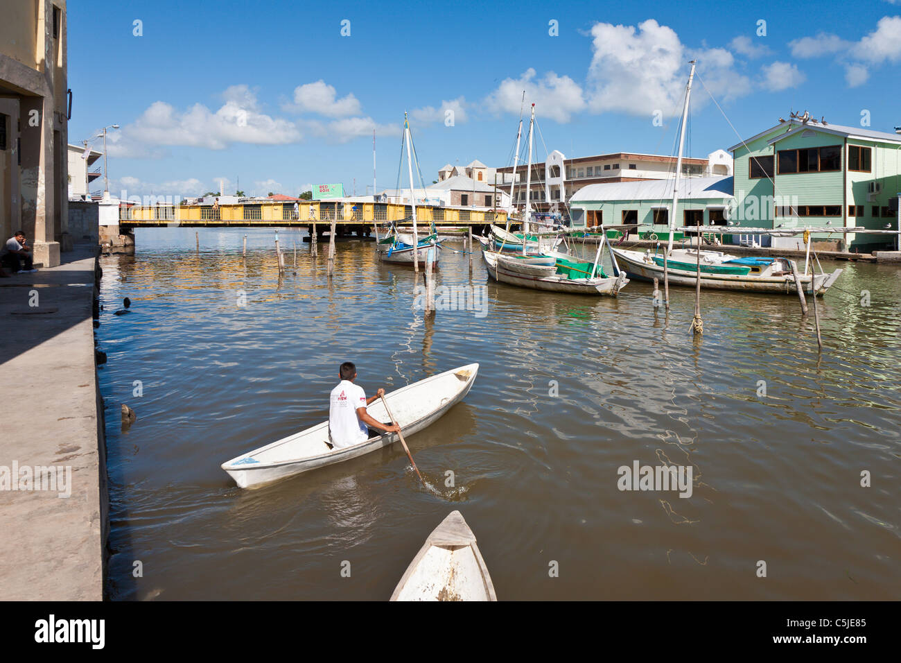 Aviron Canoë bateau type homme sur Haulover Creek, près de pont tournant, à Belize City, Belize Banque D'Images