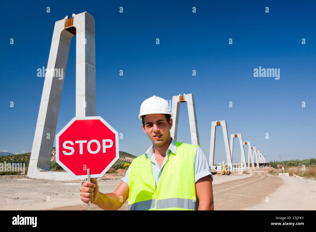 Un ouvrier de la construction où l'arrêt du trafic ferroviaire traverse une route à grande vitesse en cours de construction Banque D'Images