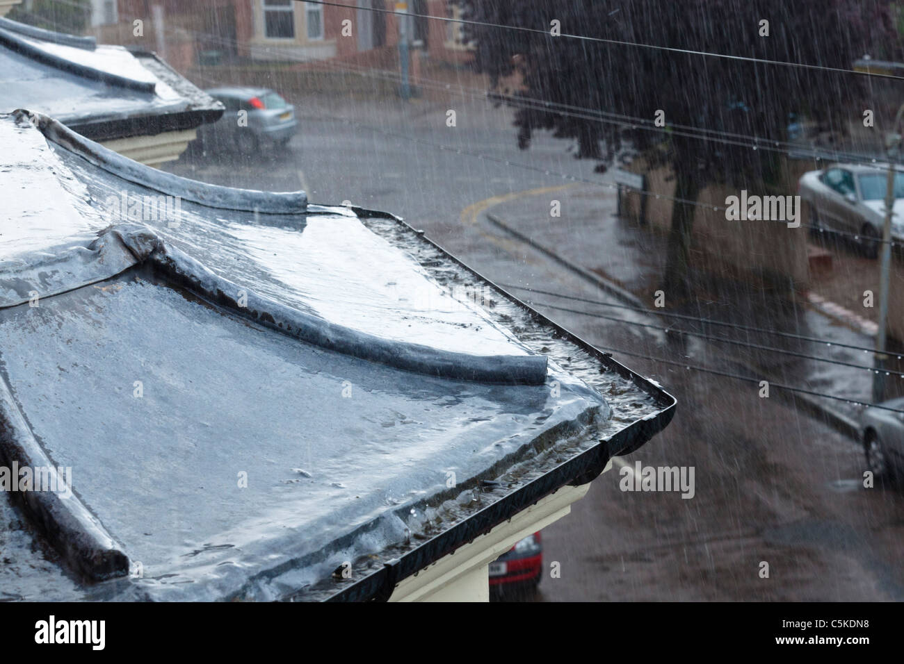 Pluie torrentielle pendant un gros orage. La forte pluie qui tombe sur un toit et gouttières avec le caniveau plein d'eau de pluie, Lancashire, England, UK Banque D'Images