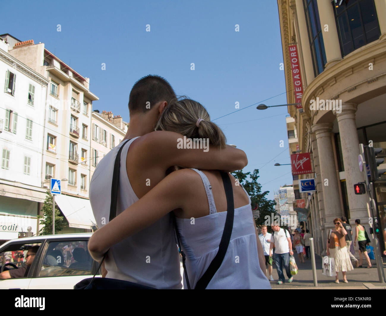 Jeune couple retour à la ronde avec les bras les uns les autres, en attente de traverser une rue, Nice, France Banque D'Images