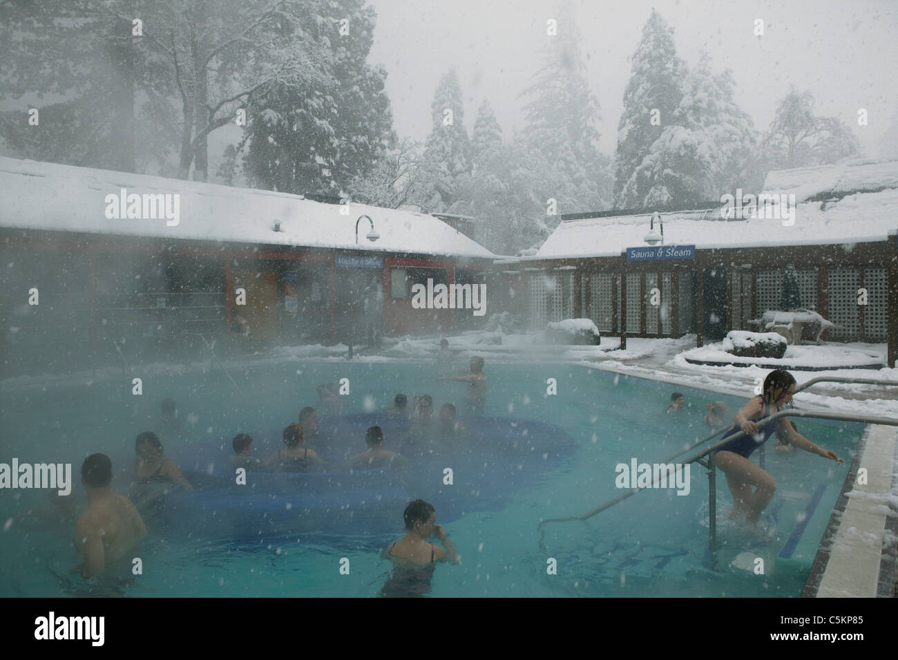 Les gens se baigner dans la neige, dans les bassin alimenté par des sources chaudes naturelles, Hanmer Springs, New Zealand Banque D'Images