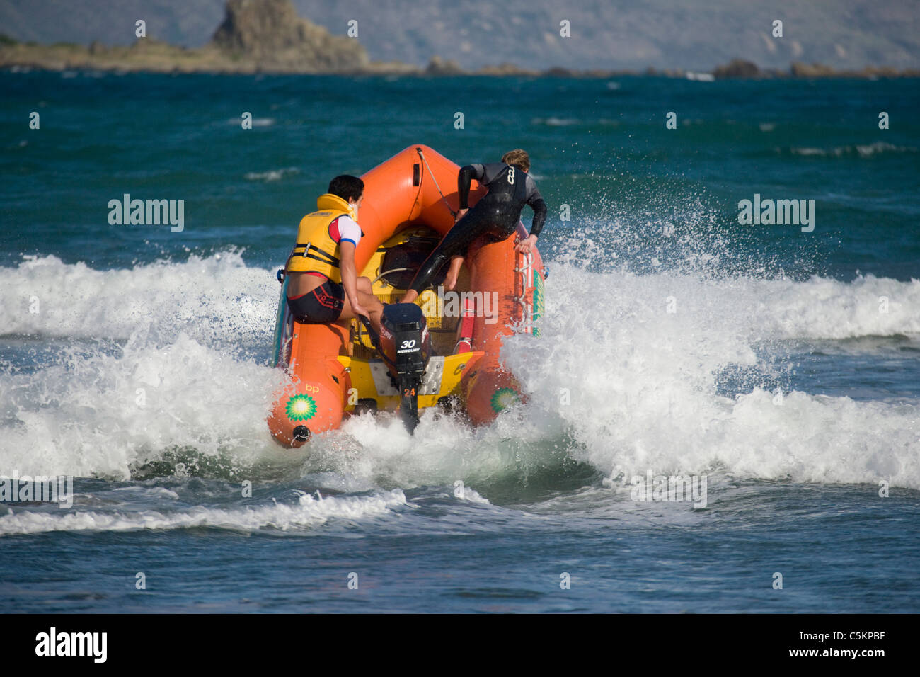 Bateau de sauvetage surf gonflable avec moteur hors-bord de la mise sous tension par vagues avec deux hommes à bord, Lyall Bay, Wellington, Banque D'Images