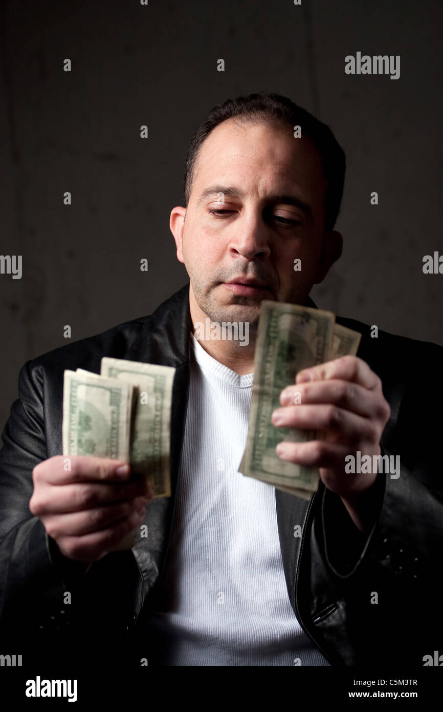 Un homme d'âge moyen comptant une poignée de one hundred dollar bills. Profondeur de champ avec l'accent sur le visage. Banque D'Images