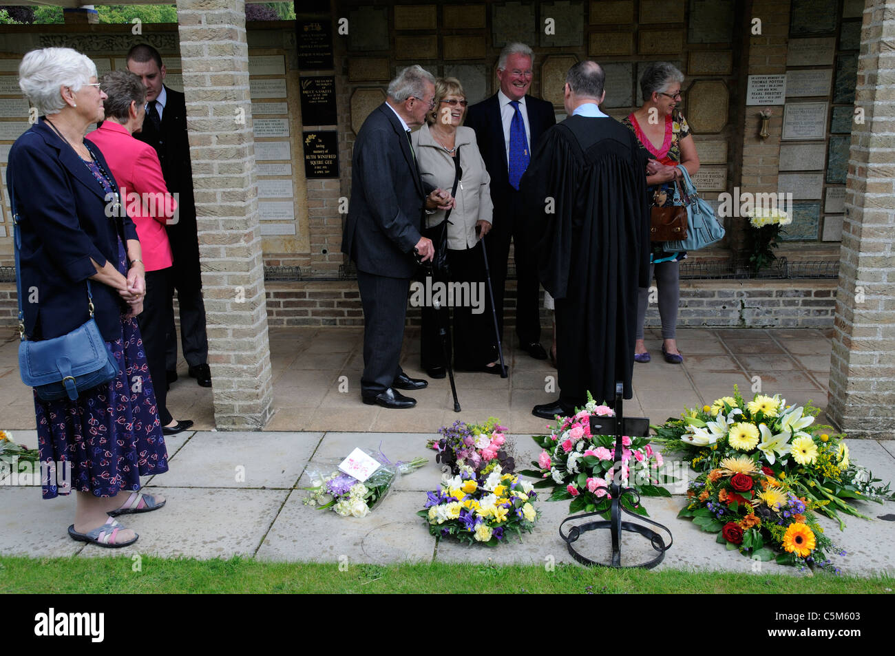 En Deuil et prêtre à un enterrement de parler et d'admirer des fleurs et des couronnes au crématorium Banque D'Images