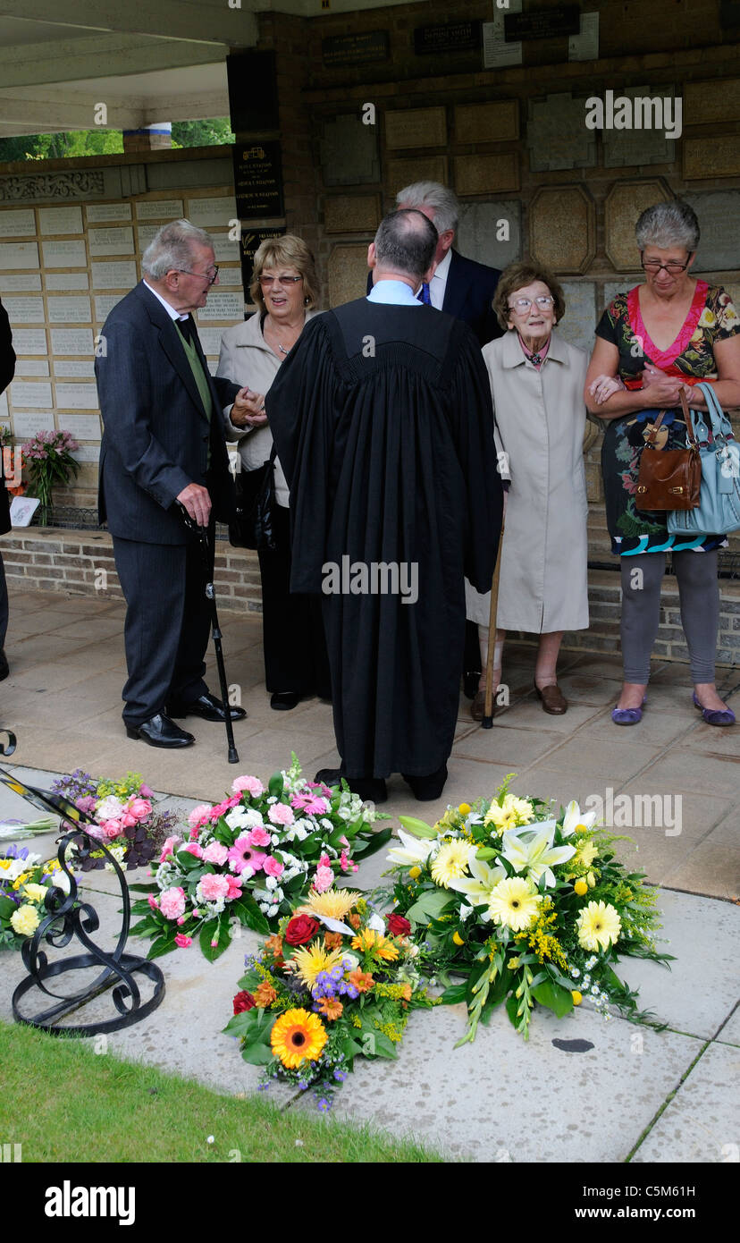 En Deuil et prêtre à un enterrement de parler et d'admirer des fleurs et des couronnes au crématorium Banque D'Images