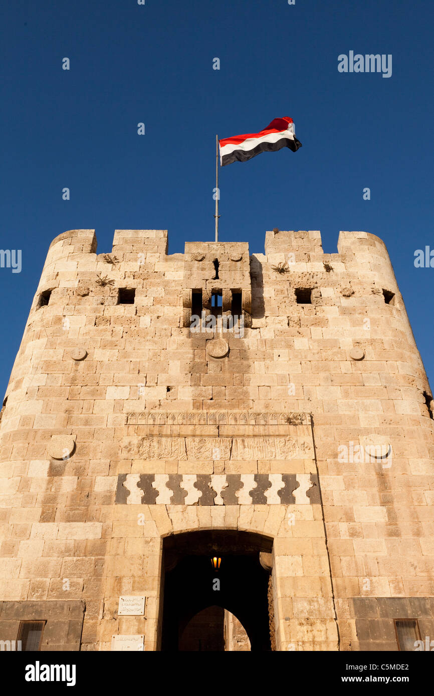 Le drapeau syrien, volant au-dessus de la passerelle de citadelle d'Alep, contre un ciel bleu Banque D'Images
