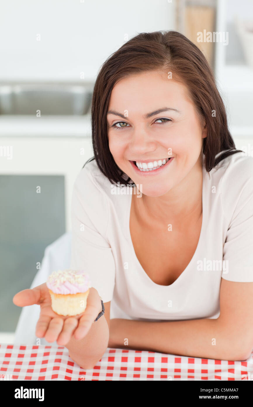 Laughing brunette montrant un petit gâteau Banque D'Images