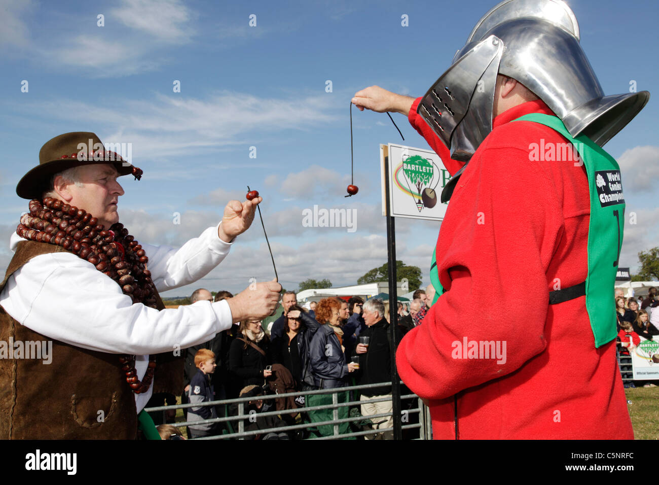 Deux hommes jouer conkers, l'un portant un casque de chevalier, lors du championnat de conker, dans la région de Castel Guelfo di Bologna, Northamptonshire Banque D'Images