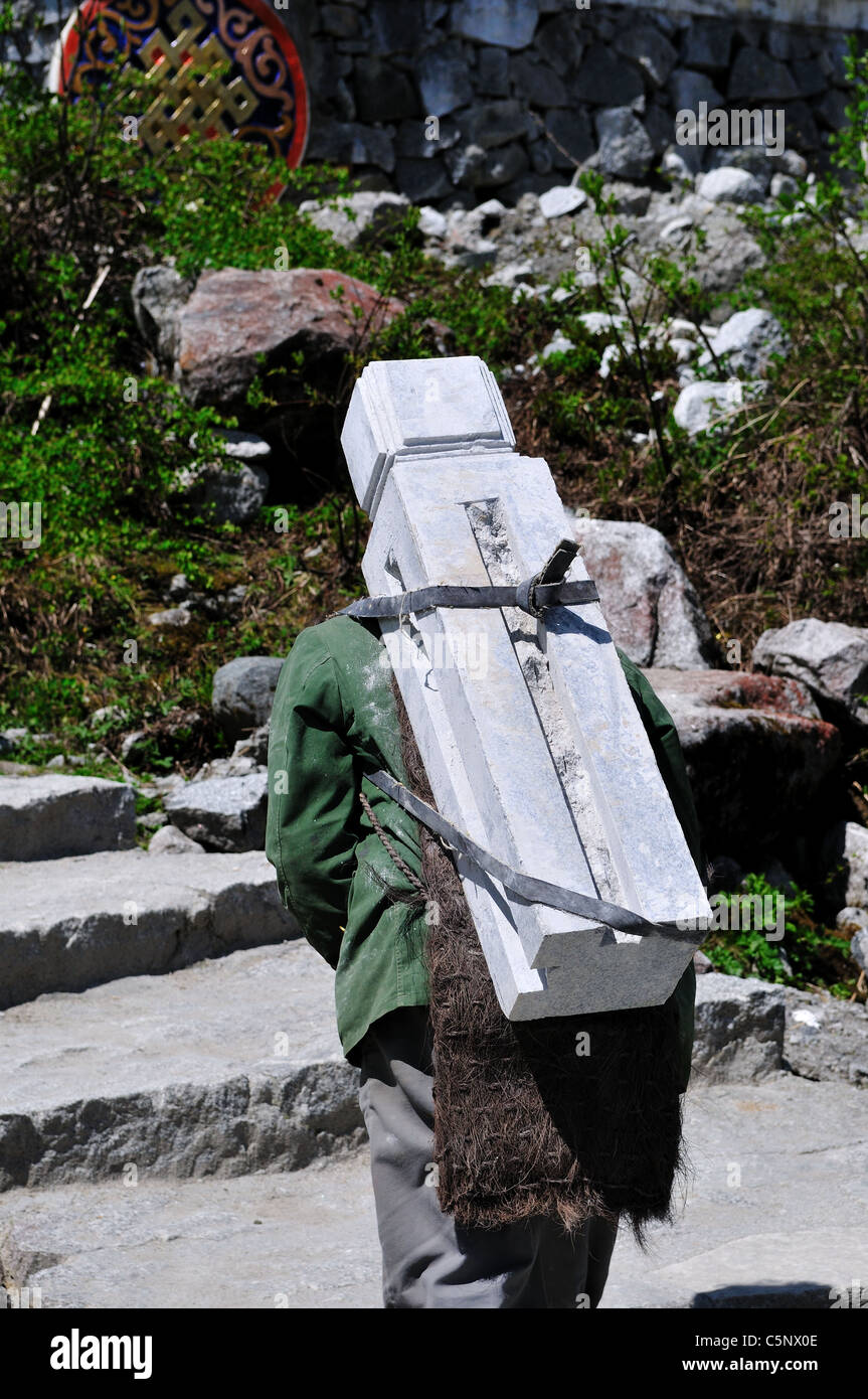 Un homme porte une lourde charge sur son dos post de pierre à la construction site. Au Sichuan, en Chine. Banque D'Images
