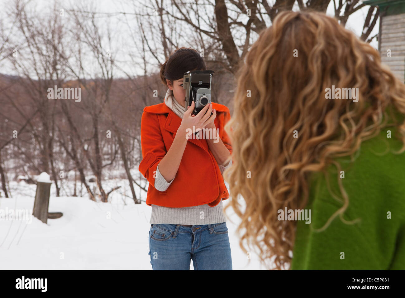 Woman taking photograph of friend in snow Banque D'Images