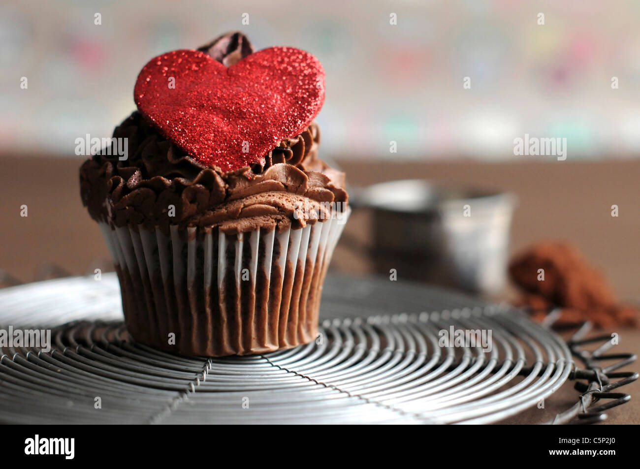 Cupcake chocolat avec du sucre sur le dessus du coeur rouge Banque D'Images