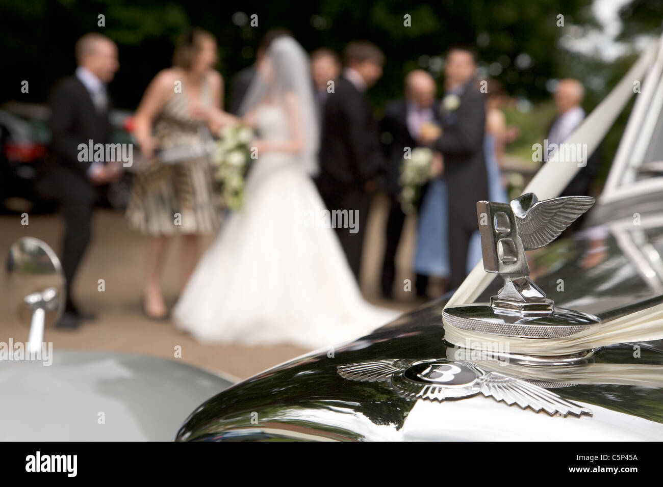 Mariée accueille les clients à la réception de mariage avec Bentley Voiture de mariage en premier plan Banque D'Images