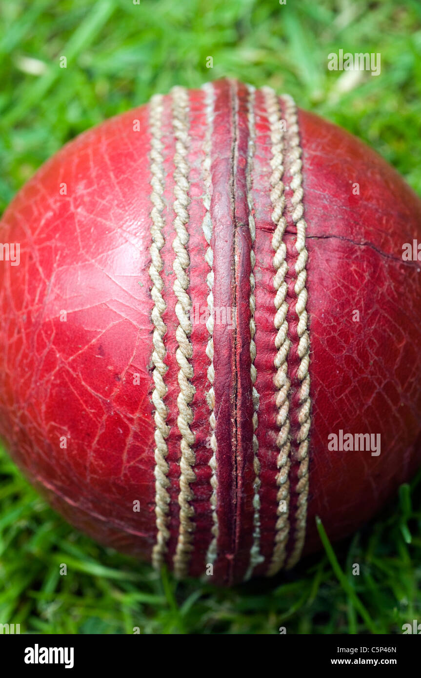 Cricket ball rouge sur l'herbe verte, CRICKET, Boule, ROUGE, SEAM, vieux, usé, EN DÉTRESSE, SPIN, seam, anglais pour l'été, l'herbe, Dave Podmore Banque D'Images