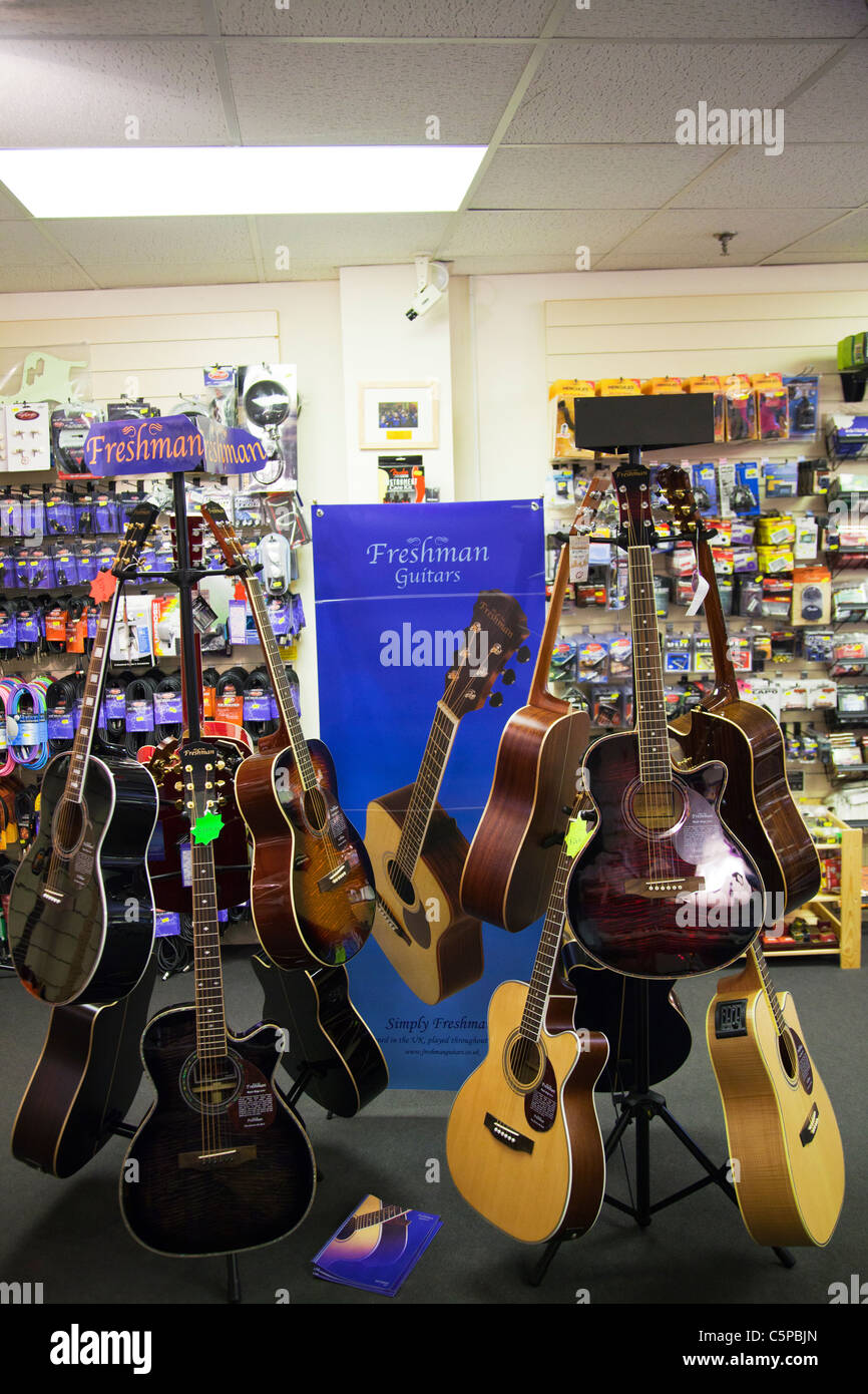 Nouveau support de guitare dans un magasin de musique guitares montrant pour la vente au public sur l'écran acoustique & électrique Banque D'Images