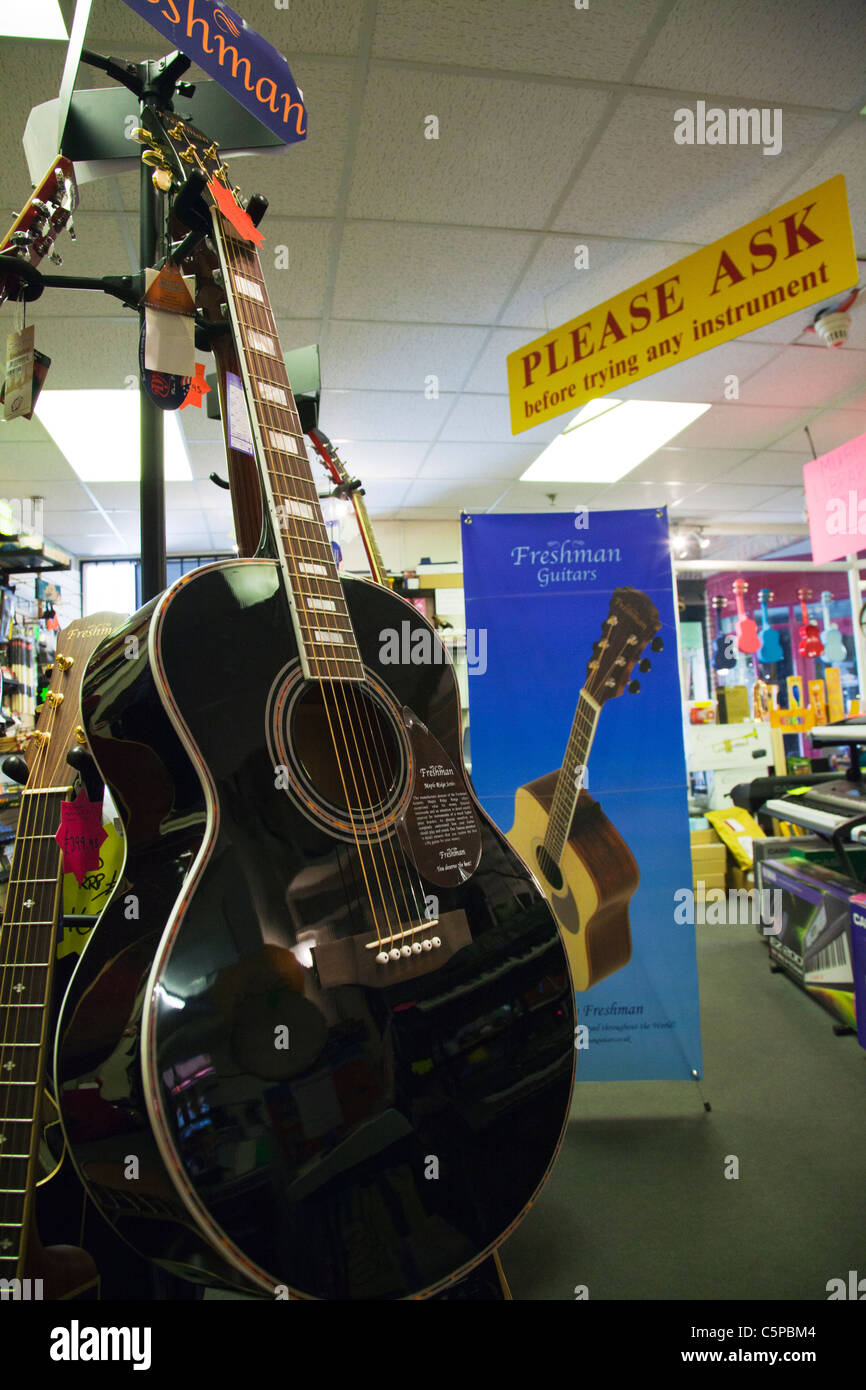 Nouveau support de guitare dans un magasin de musique guitares montrant pour la vente au public sur l'écran acoustique & électrique Banque D'Images