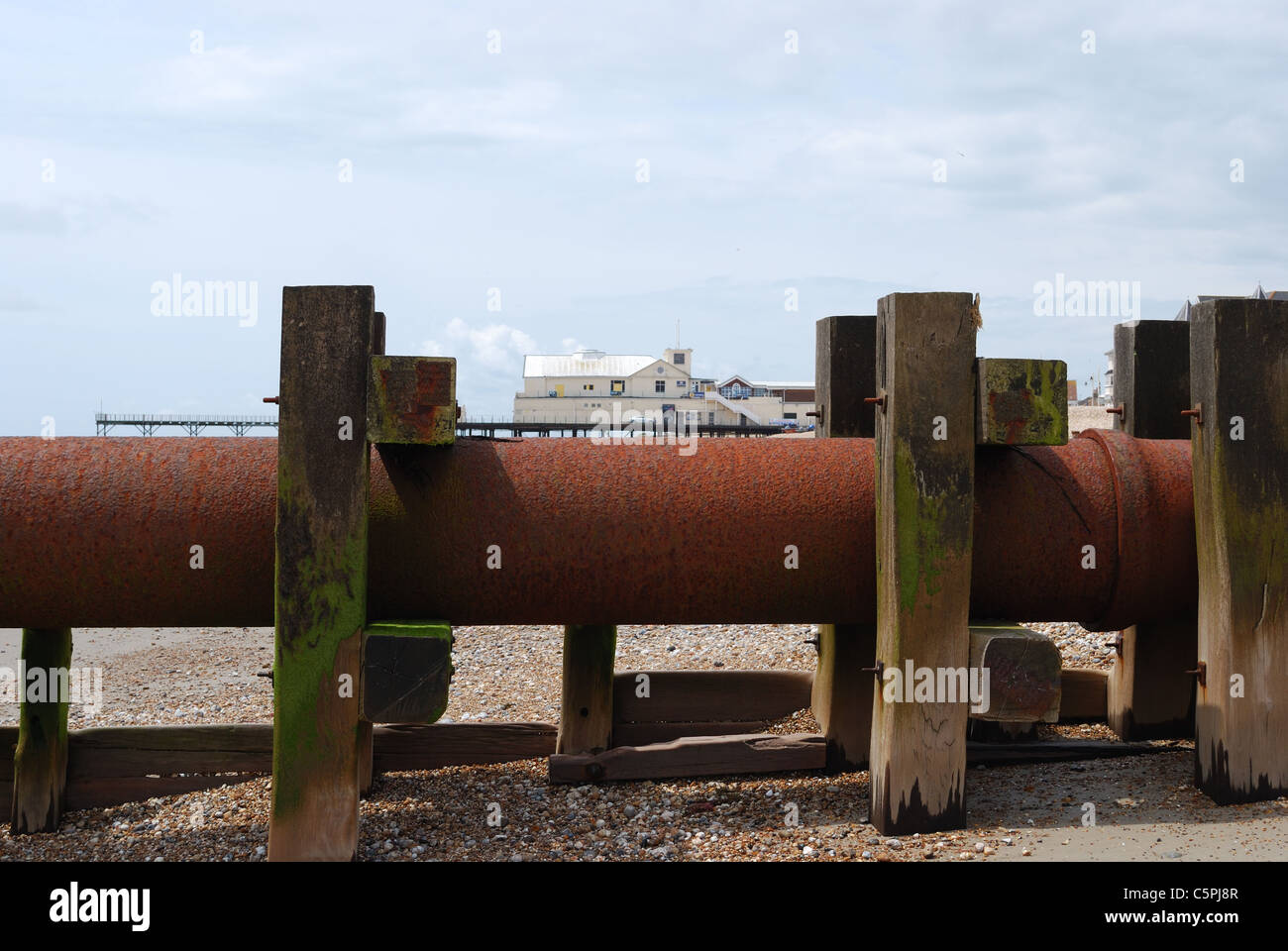 Émissaire de rouillé sur une plage avec une jetée en arrière-plan. Journée ensoleillée avec tuyau d'égouts n'est pas oxydée. Banque D'Images