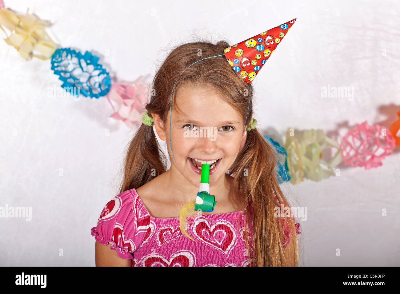 Fillette de huit ans avec party hat et la trompette sur un Children's Festival Banque D'Images