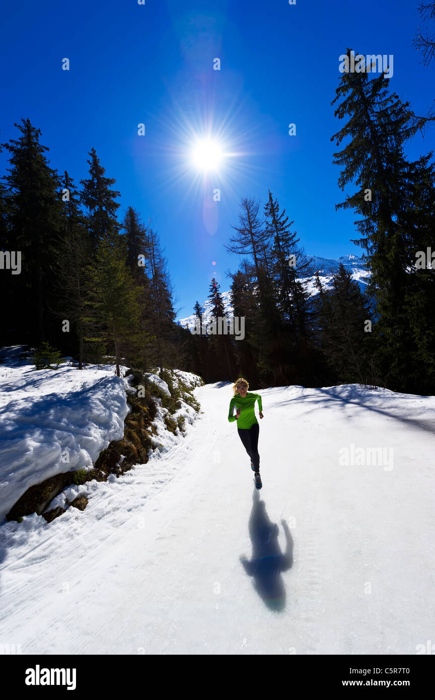 Une fille jogging à haute altitude dans les montagnes enneigées. Banque D'Images