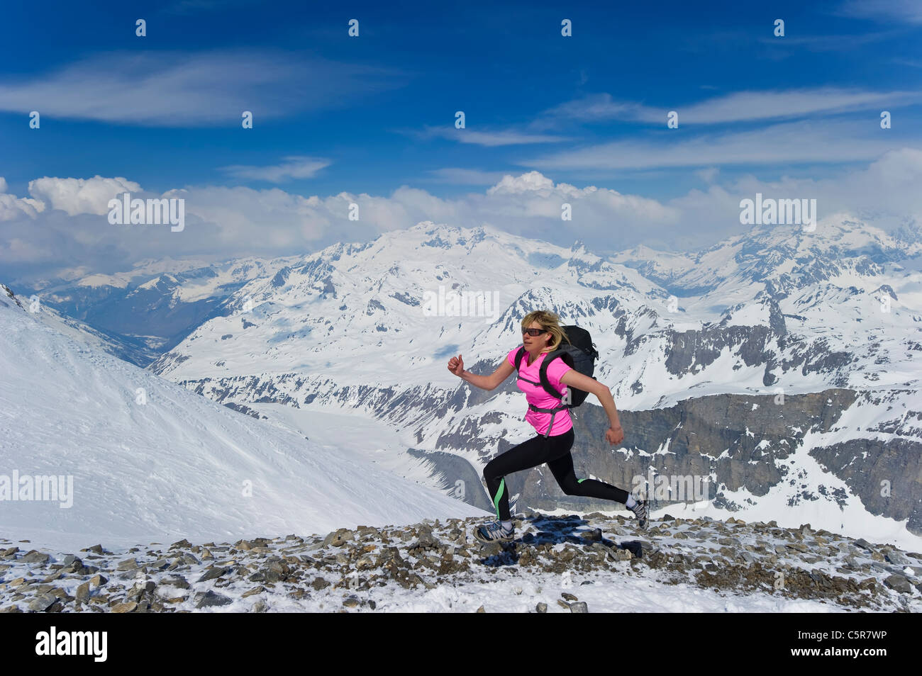 Une femme tourne vite à travers les montagnes enneigées. Banque D'Images