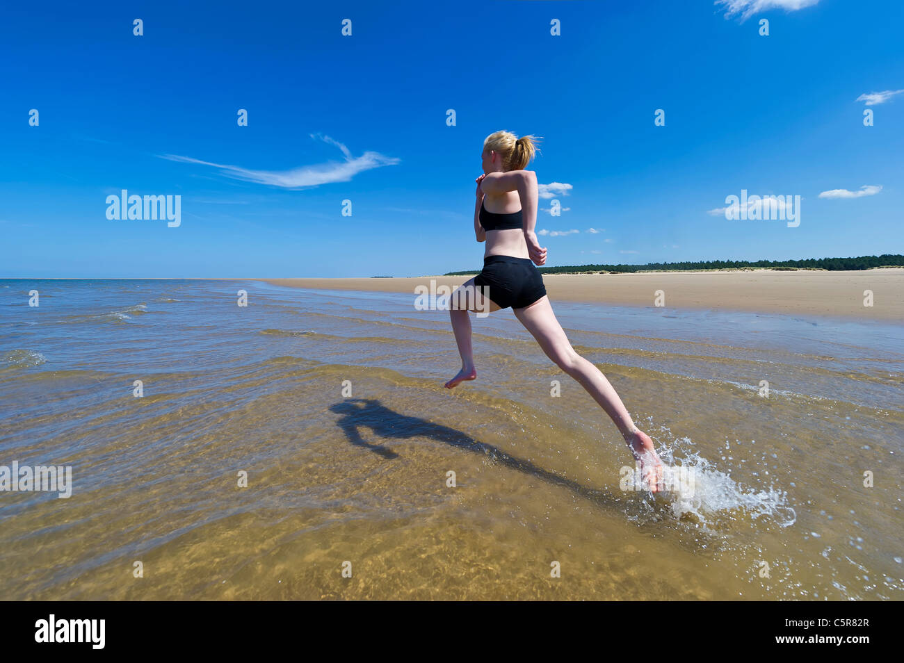 Un jogger fonctionnant par les vagues de l'océan. Banque D'Images