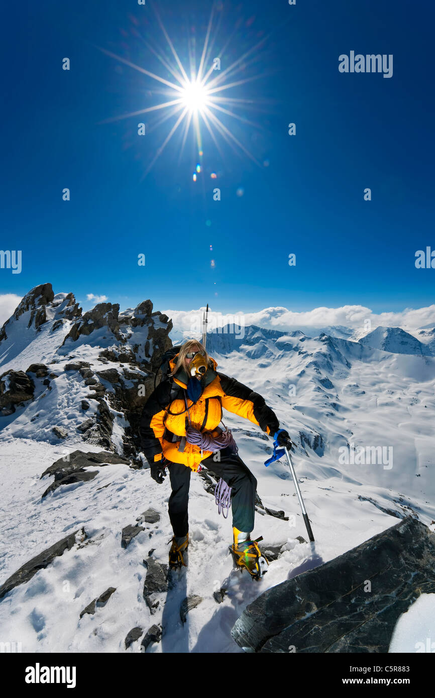 L'alpiniste sur monter jusqu'au sommet de la montagne enneigée au-dessus les nuages, les sommets et les crêtes. Banque D'Images
