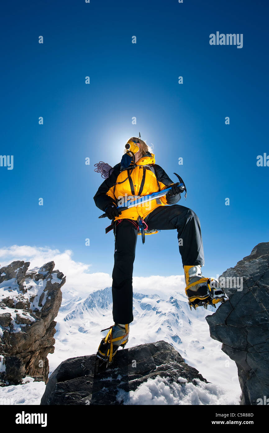 Alpiniste féminine se tient au-dessus des sommets avec masque à oxygène, piolets et crampons. Banque D'Images