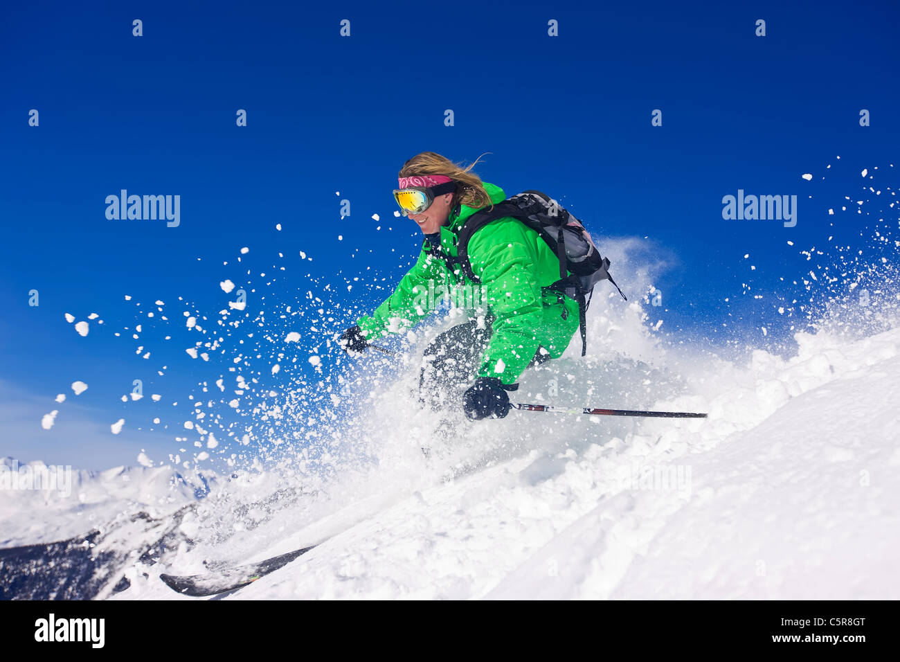 Un skieur skis vite par les montagnes enneigées. Banque D'Images