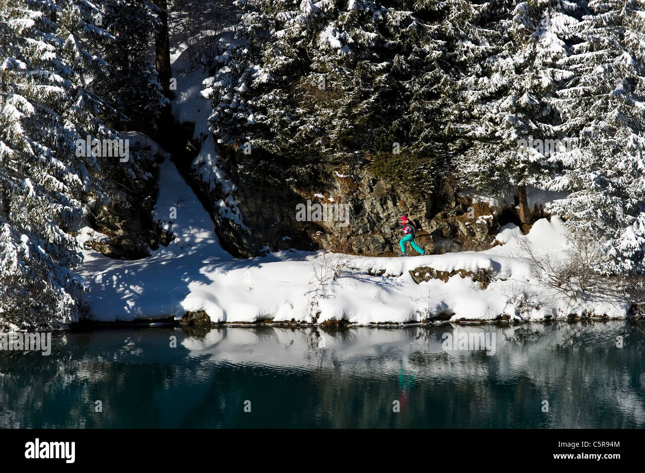 Une femme en raquettes à neige hiver jogging passé un lac. Banque D'Images
