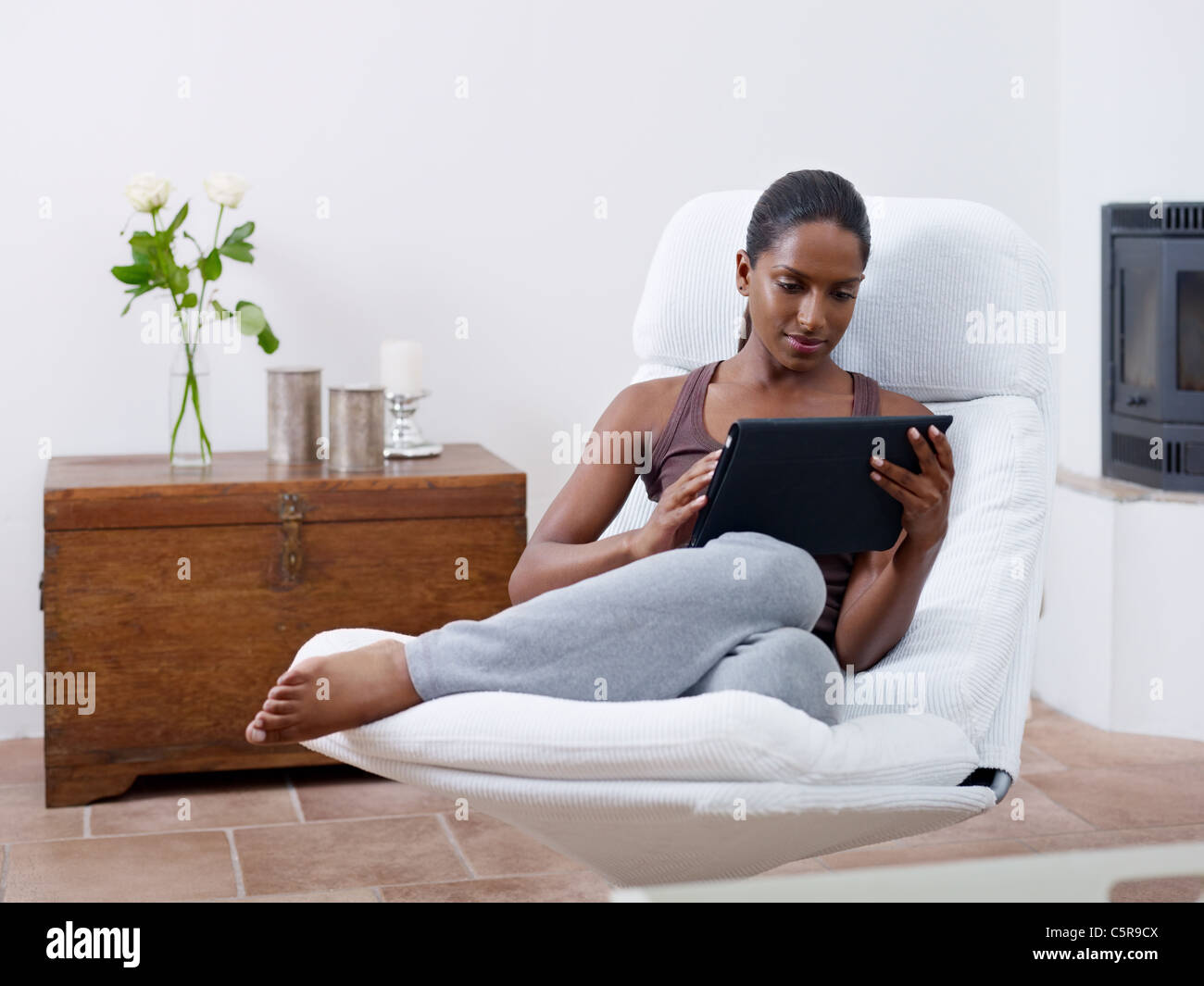 Mid adult woman relaxing on fauteuil et l'utilisation de l'ordinateur tablette tactile. Vue avant, de forme horizontale, copy space Banque D'Images