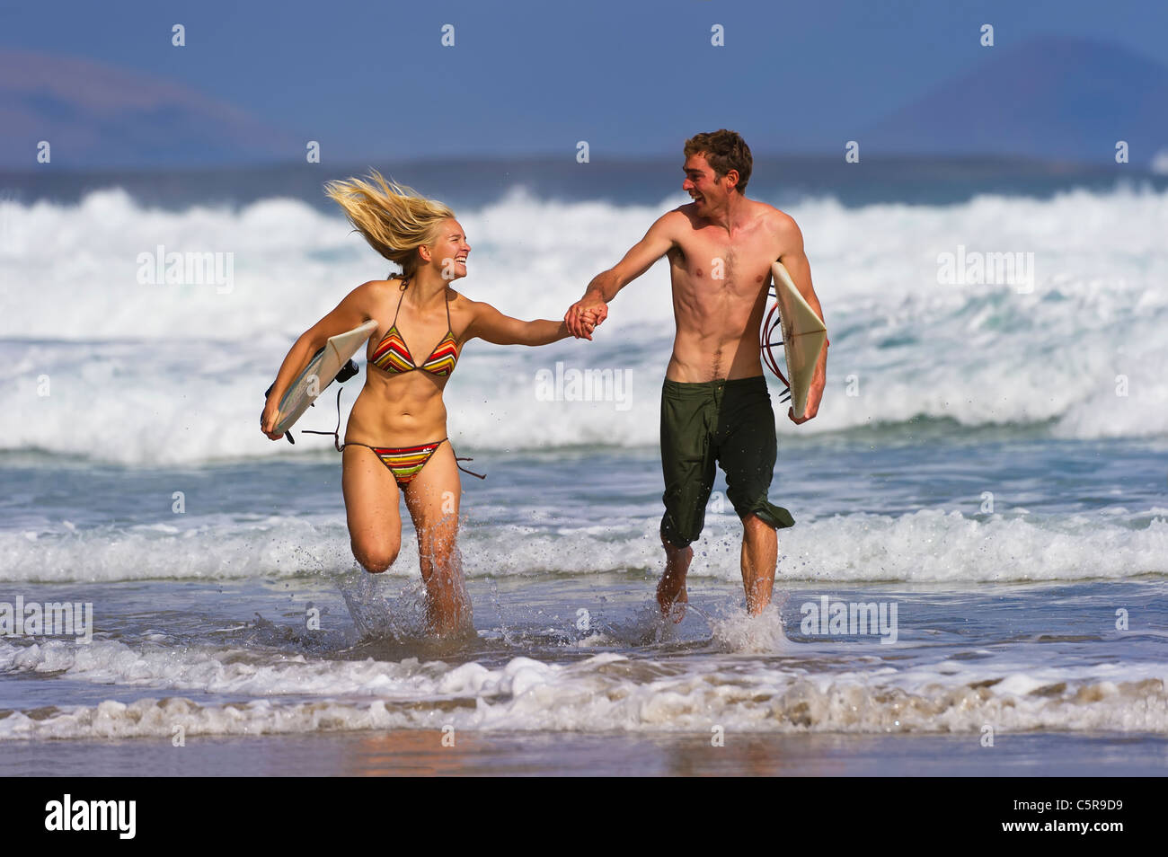 Un jeune couple s'exécutant dans le surf. Banque D'Images