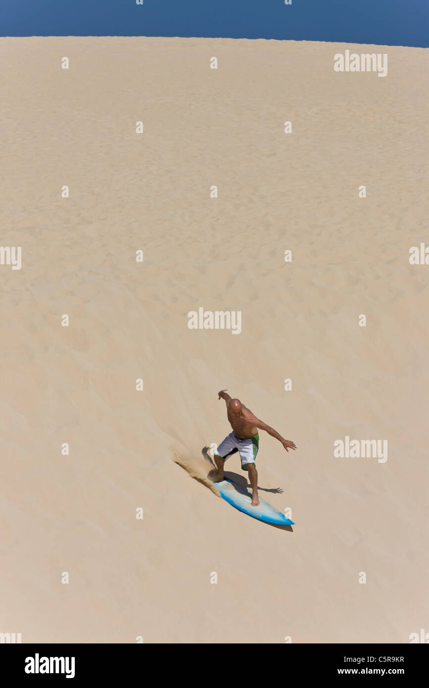 Un surfeur surf une immense dune de sable. Banque D'Images