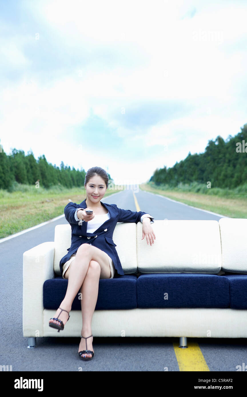 A woman sitting on sofa holding remote control Banque D'Images