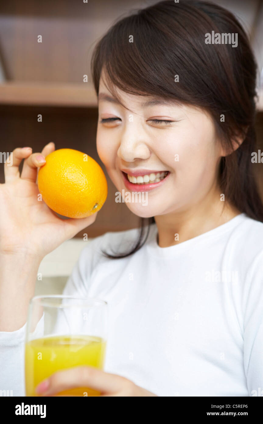 Une femme tenant une orange et le jus d'orange Banque D'Images