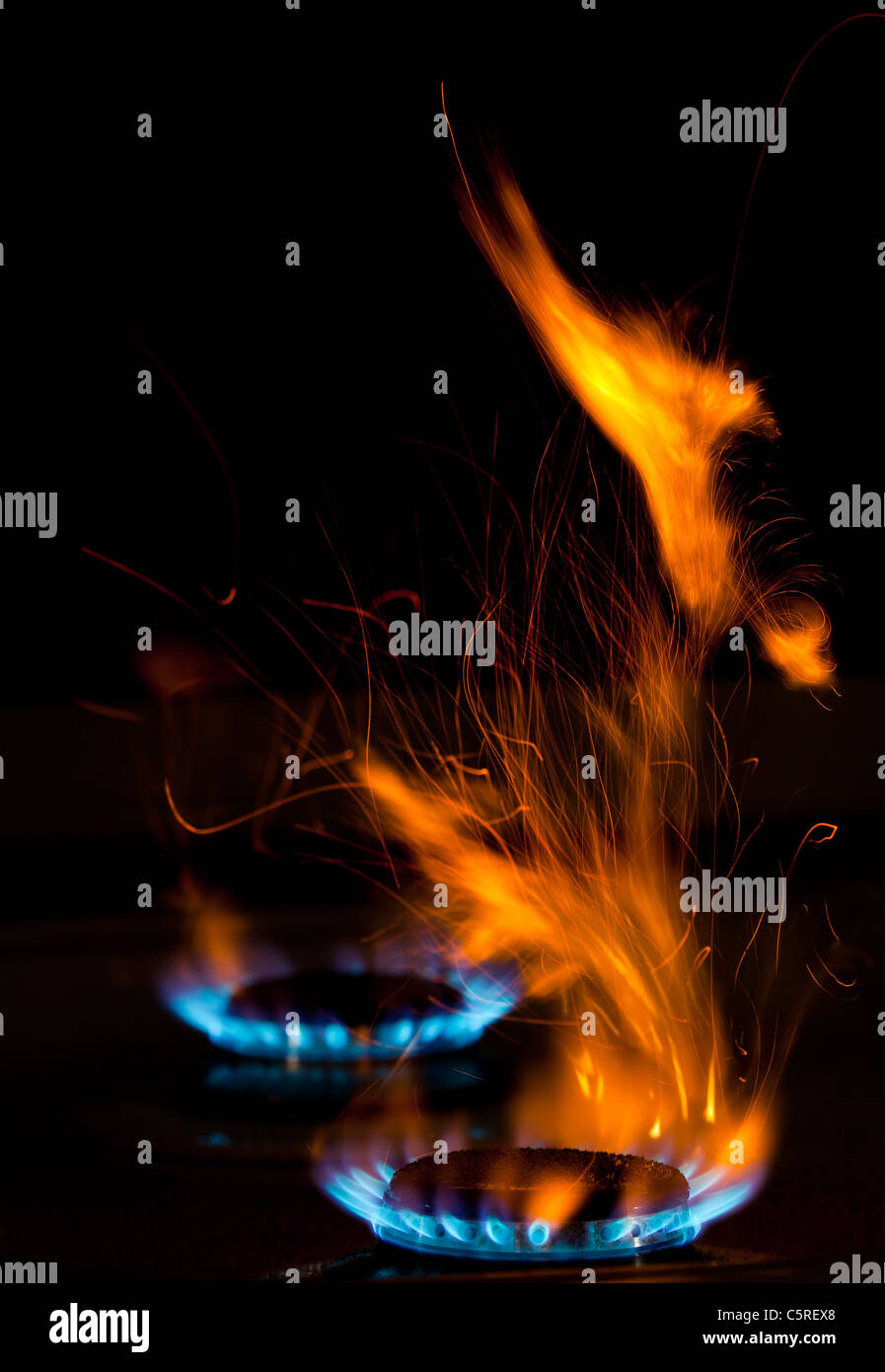 Des étincelles et des flammes au-dessus de cuisinière à gaz brûlant de flammes bleues Banque D'Images