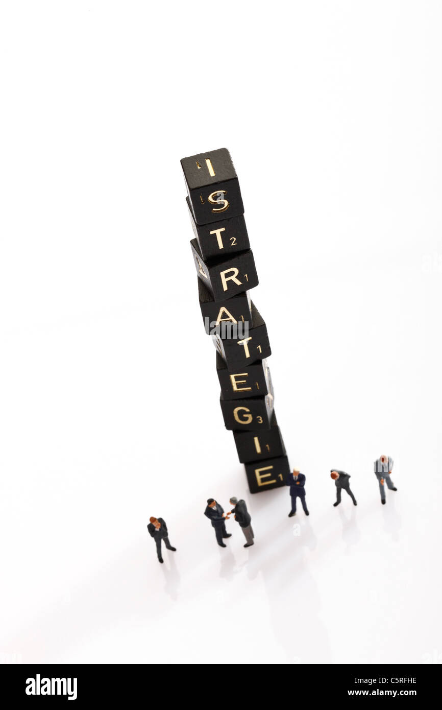 Tuiles de Scrabble empilées formant le mot stratégie, en premier plan business men figurines, elevated view Banque D'Images
