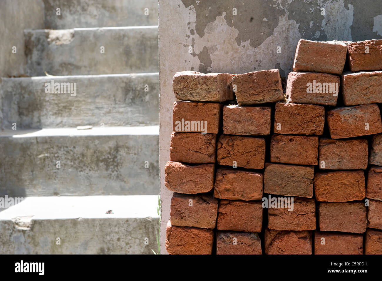 Escaliers en béton avec un tas de briques de boue dans la lumière du soleil Banque D'Images