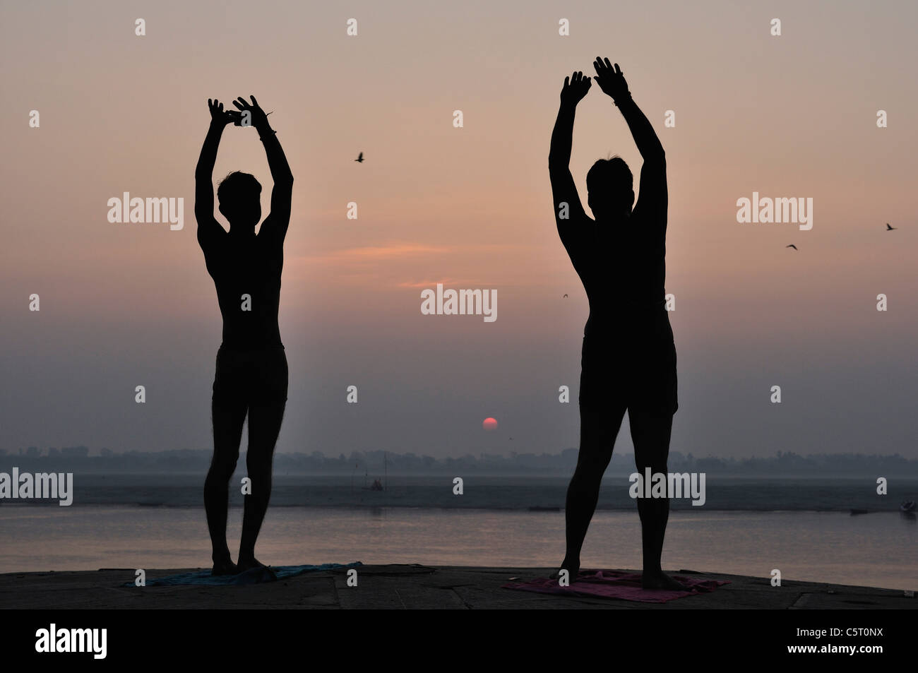 L'Inde, Uttar Pradesh, Varanasi, la silhouette de deux hommes faisant lever du soleil rituel à River Ganges Banque D'Images