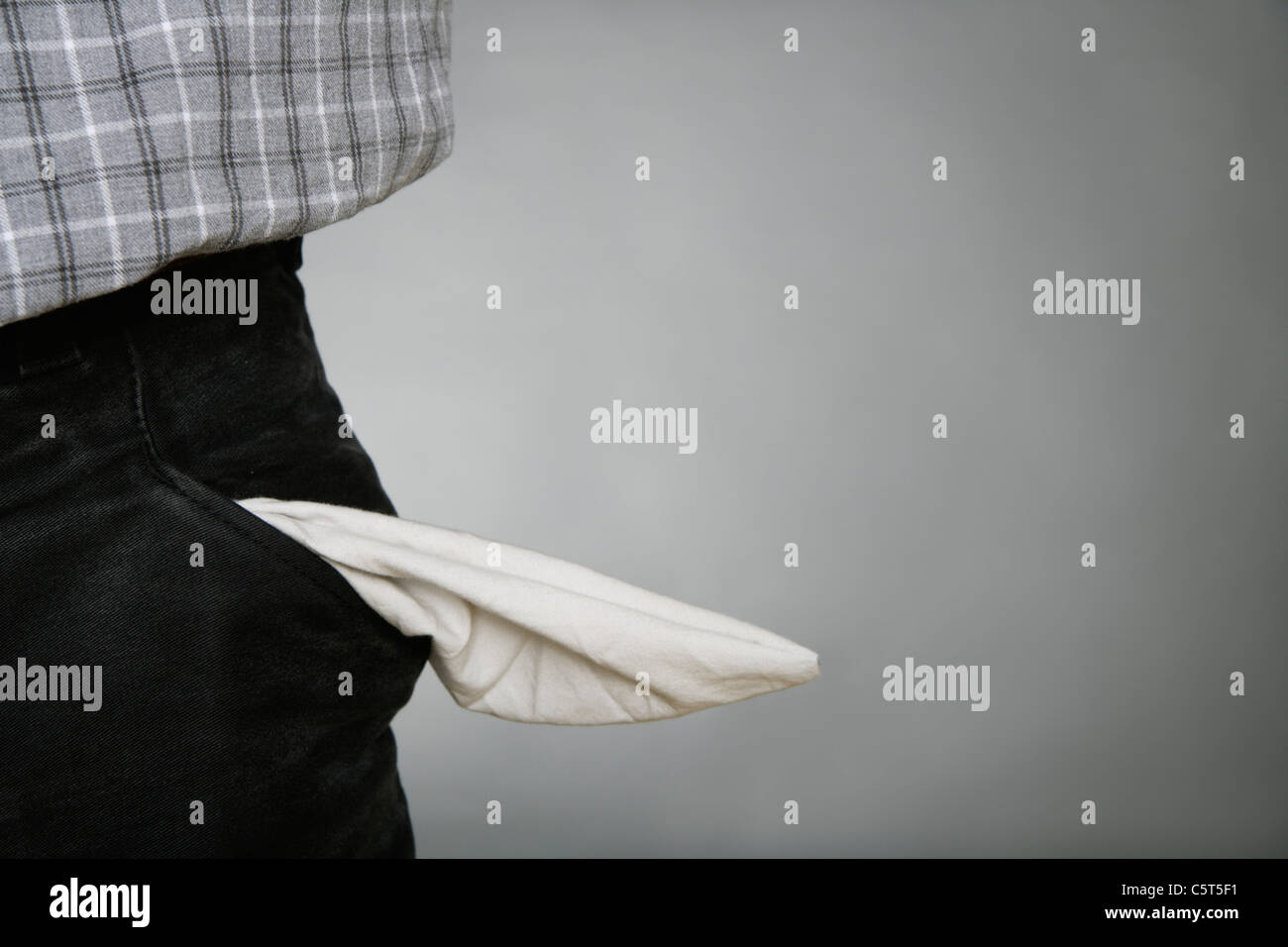 Close up of man avec poche vide contre l'arrière-plan gris Banque D'Images