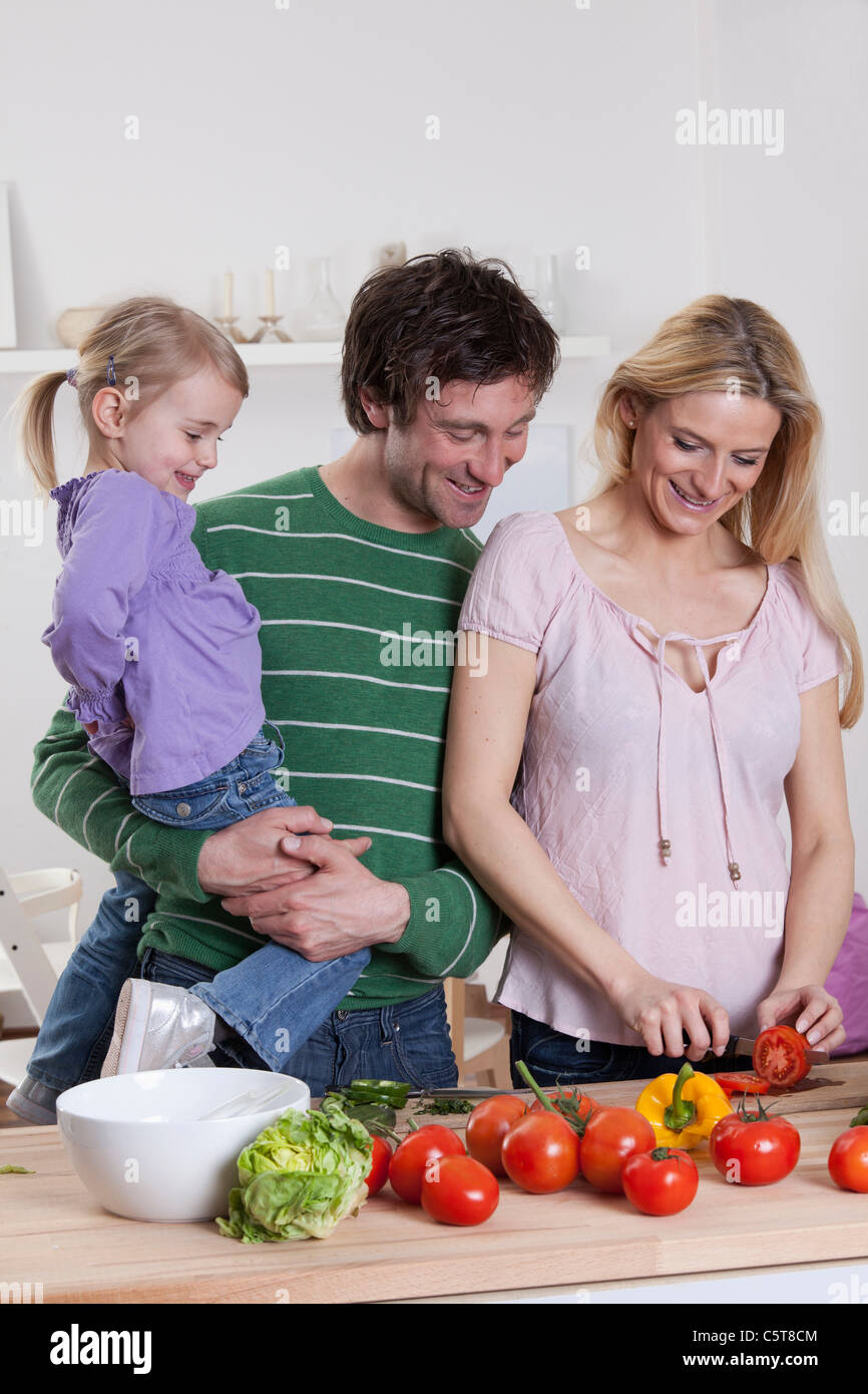 Germany, Bavaria, Munich, mère de préparer la salade avec le père et la fille debout à côté de sa Banque D'Images