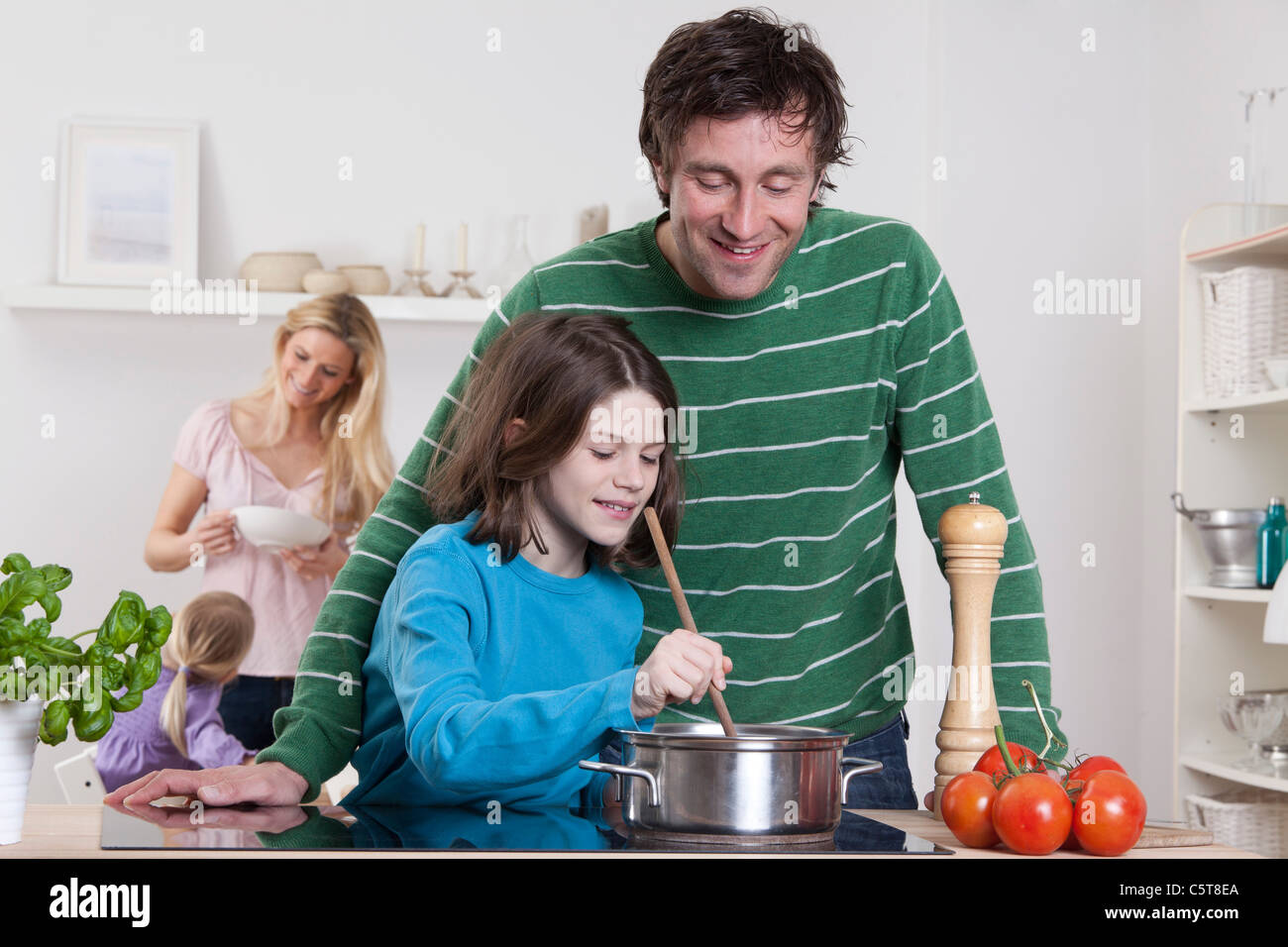 Germany, Bavaria, Munich, fils de cuisiner avec le père, la mère et la fille en arrière-plan Banque D'Images