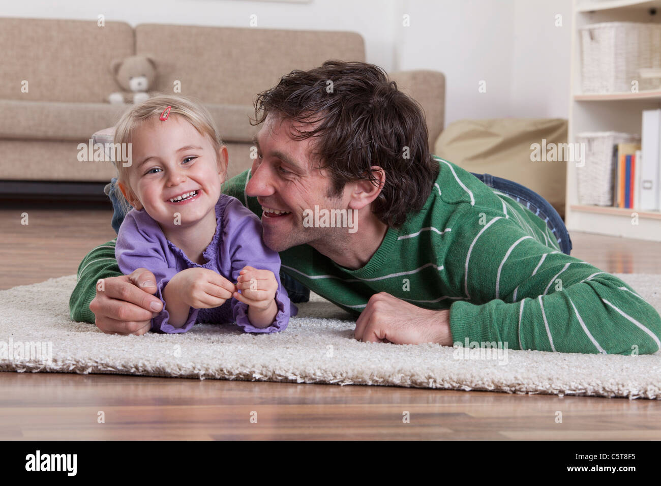 Germany, Bavaria, Munich, père et fille, allongé sur le tapis, smiling Banque D'Images