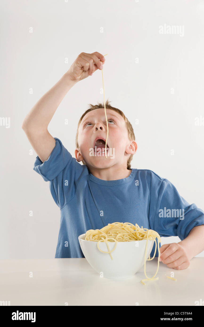 Boy (6-7) de manger des nouilles Spaghetti unique Banque D'Images