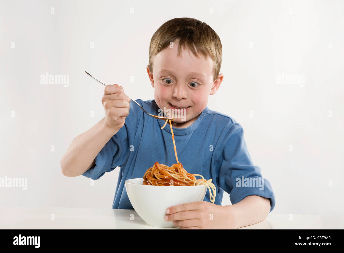 Boy (6-7) eating spaghetti, portrait Banque D'Images