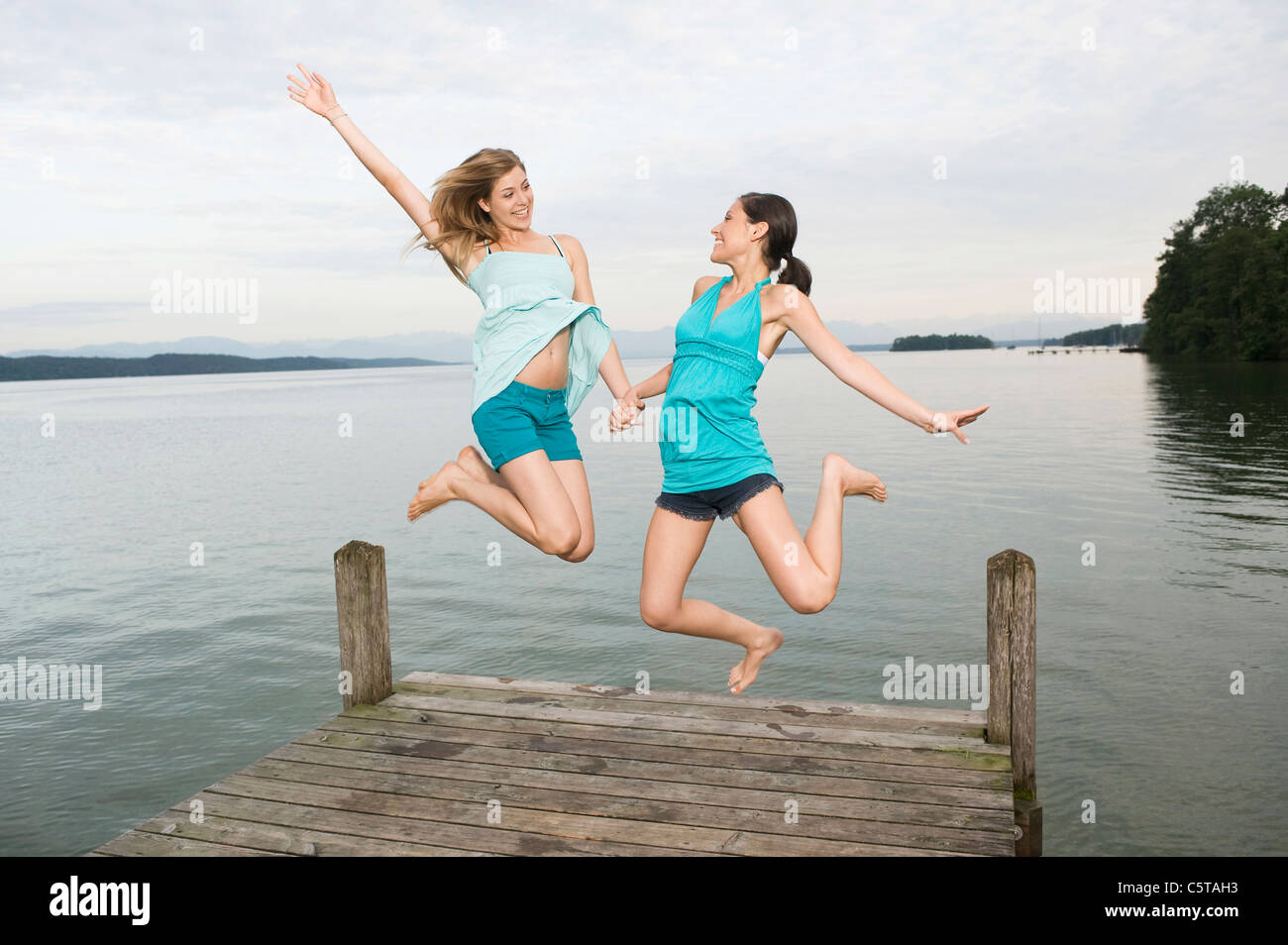 Allemagne, Berlin, deux jeunes femmes sautant sur jetty, rire, portrait Banque D'Images