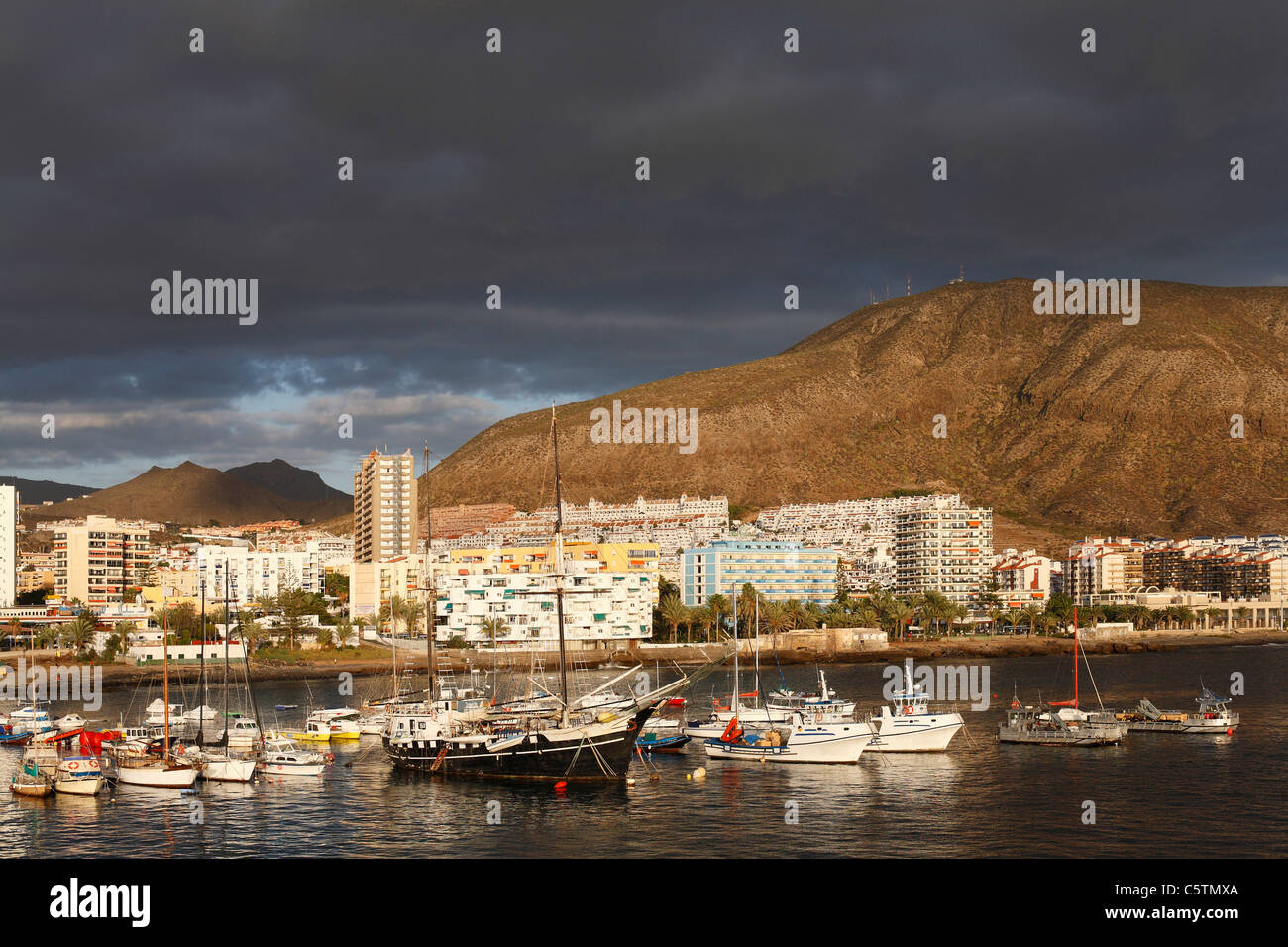 L'Espagne, Iles Canaries, Tenerife, Los Cristianos, vue de bateaux dans l'eau avec les immeubles et les montagnes en arrière-plan Banque D'Images
